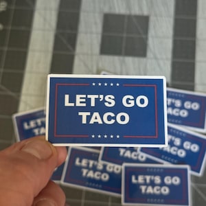 May include: A rectangular sticker with a blue background and the text "LET'S GO TACO" in white. The sticker has a red border and small white stars. Several stickers are visible.