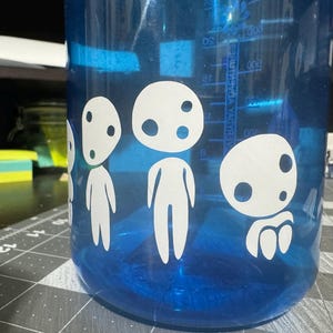 May include: A blue water bottle with white vinyl stickers of four characters from the animated film "My Neighbor Totoro".