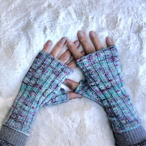 May include: A pair of teal, pink, and white fingerless gloves with a ribbed knit pattern.