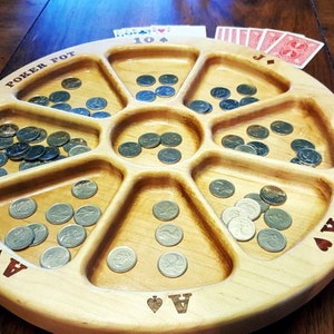 May include: A wooden poker chip tray with eight compartments, each filled with silver poker chips. The tray is labeled "Poker Pot" and "1889 Sequence".