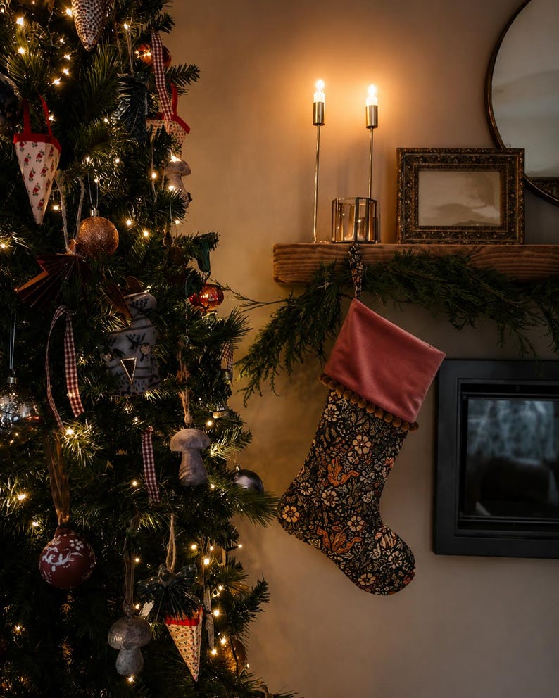 May include: A decorated Christmas tree with ornaments and lights, next to a fireplace. A patterned Christmas stocking hangs from the mantel. Two lit candles and a framed picture are also on the mantel.