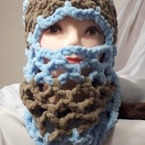May include: A handmade, crocheted balaclava in a two-tone design. The hat features a combination of light blue and brown yarn, with a textured, open-weave pattern around the face and neck. The balaclava is designed to cover the head and neck.
