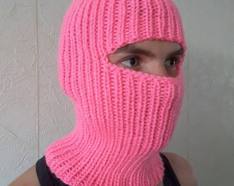 Puede incluir: Una balaclava de punto rosa con un agujero para los ojos y la boca.