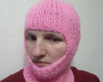 Puede incluir: Una balaclava de punto rosa con un agujero para los ojos y la boca.