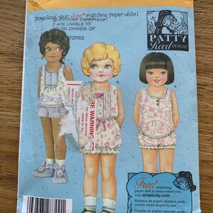 Op de afbeelding: Simplicity patroon 4814 met drie papieren poppen in bijpassende outfits. De verpakking bevat de tekst "Download je gratis bijpassende papieren poppen!" en "Patty Reed Designs."