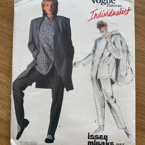 May include: Vintage Vogue Patterns Individualist sewing pattern featuring a woman in a gray coat and pants. The pattern includes a drawing of a suit with the text "Issey Miyake 1664". The cover is off-white with red and black text.