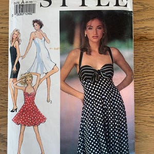 May include: A vintage sewing pattern labelled "STYLE" with dress illustrations. The pattern includes a black and white polka dot dress, a black dress, a white dress, and a red polka dot dress. The size is A (6-16).