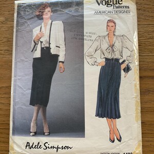 Op de afbeelding: Een vintage Vogue Patterns naaipatroon met ontwerpen van Adele Simpson. De omslag toont illustraties van dameskleding, waaronder een blazer- en rokensemble en een blouse met een geplooide rok. Het patroonnummer is 1483.