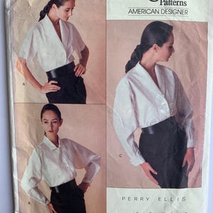 Puede incluir: Patrón de costura Vogue Patterns American Designer para una blusa blanca con cuello y mangas largas. El patrón es de Perry Ellis y está clasificado como fácil de coser. El número del patrón es 2091.