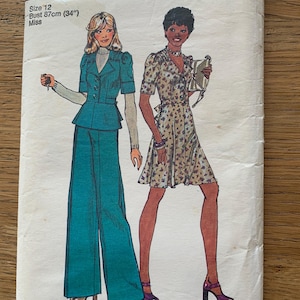 May include: Vintage Simplicity sewing pattern featuring illustrations of two women in 1970s fashions. The pattern includes a teal pantsuit and a floral print dress. The bust size is 34 inches (87cm). The pattern is labeled "Brown".