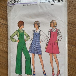 May include: Vintage sewing pattern labelled "Style" with the number 4358. The pattern shows illustrations of three outfits: a green jumpsuit, a blue and white checked dress, and a pink dress. The pattern is on slightly worn, off-white paper.