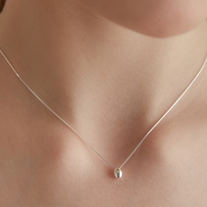 May include: A silver chain necklace with a small, round pendant.
