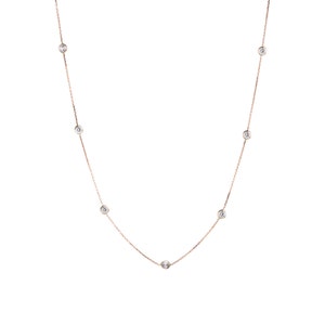 Puede incluir: Un delicado collar de cadena de oro con siete pequeñas piedras redondas transparentes.