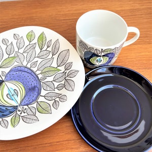 以下が含まれることがあります： 青と緑の花柄が描かれた白い陶磁器のティーカップとソーサー。ソーサーは濃い青一色です。