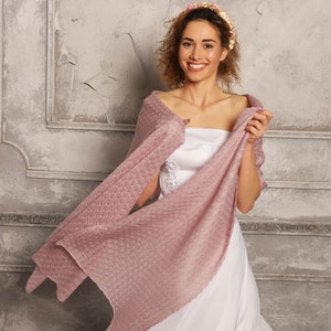 May include: A dusty rose knitted shawl with a textured, open-weave pattern draped over a white strapless dress. The lightweight, semi-sheer fabric features a consistent grid-like stitch throughout, providing a soft, layered appearance for the garment.