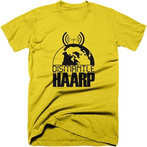 Può includere: Maglietta gialla con una grafica nera di un globo con antenne e il testo "Dismantle HAARP".