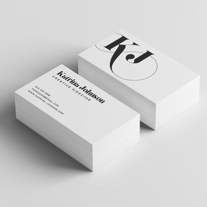 Puede incluir: Una pila de tarjetas de visita blancas con texto negro. La tarjeta superior presenta un monograma estilizado de las letras "KJ". El texto de la tarjeta dice "Kairina Johnson, Directora Creativa, +1 212 555 1212, yourname@email.com, www.kairinajohnson.com"