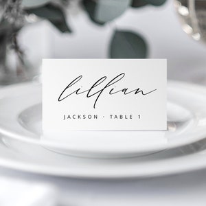 May include: White place card with black calligraphy that reads "Lillian Jackson Table 1".