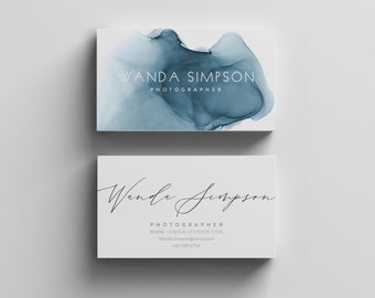 May include: A business card with a blue watercolor design. The text on the card reads "Wanda Simpson, Photographer, www.ionica-studios.com, Wanda.Simpson@ionica.com, 342.989.6789".