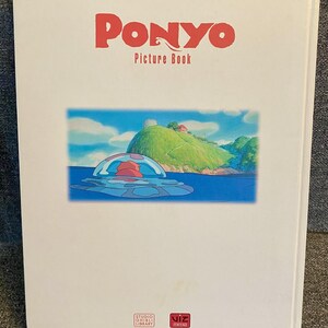May include: A white "Ponyo Picture Book" with red text. The cover features a colorful illustration of a sea scene with a red and blue jellyfish-like creature. The book is from Studio Ghibli Library and Viz Media.