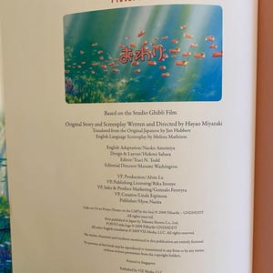 May include: Open book page featuring the title "PONYO Picture Book" in red letters. The image shows an underwater scene with fish. Text in Japanese and English details the book's creators and publisher.