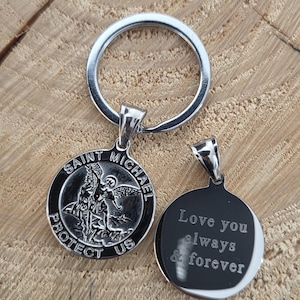 May include: A silver Saint Michael pendant keyring. The front of the pendant features an image of Saint Michael and the words "Saint Michael Protect Us". The back of the pendant has the words "Love you always & forever".