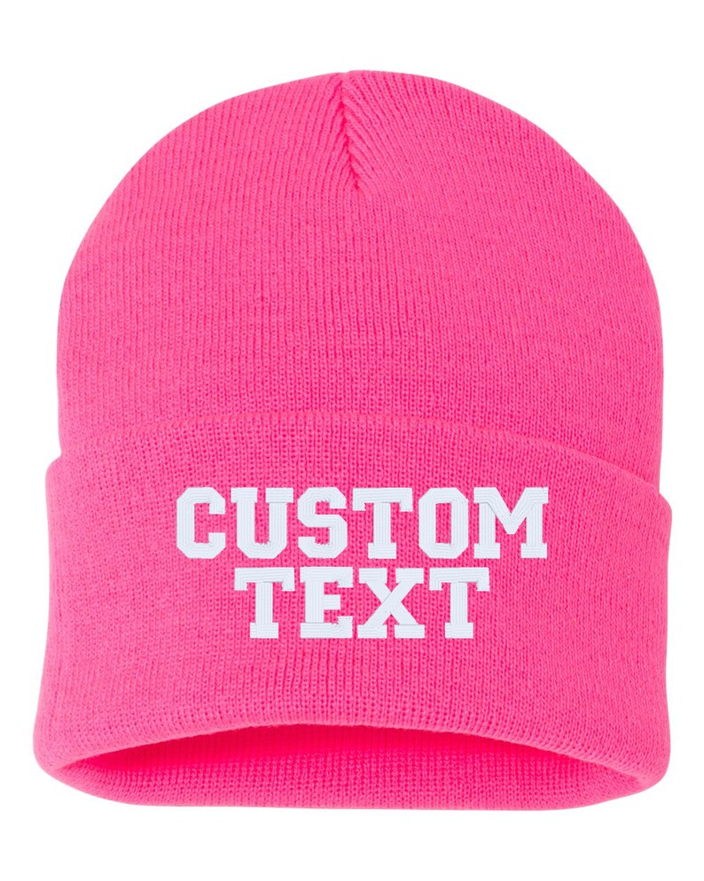 May include: A bright pink beanie with white text that reads "CUSTOM TEXT".
