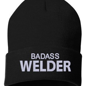 May include: Black knit beanie with white embroidered text that reads "BADASS WELDER".