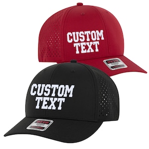Può includere: Due cappellini da baseball con rete sul retro e visiera curva. I cappellini sono neri e rossi con testo bianco che dice "CUSTOM TEXT".