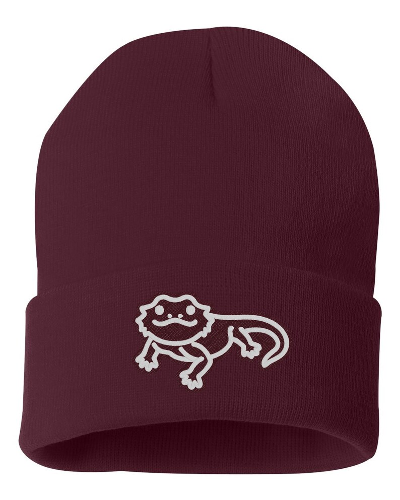 May include: A maroon beanie with a white outline of a bearded dragon on the front.