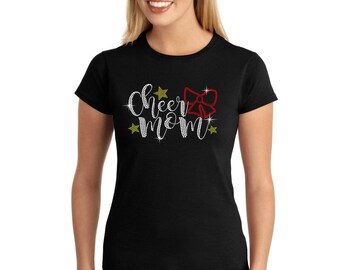May include: Black t-shirt with the words "Cheer Mom" in white rhinestones and a red rhinestone bow. There are gold star rhinestones around the text.