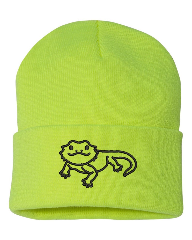 May include: A bright yellow beanie with a black embroidered bearded dragon design.