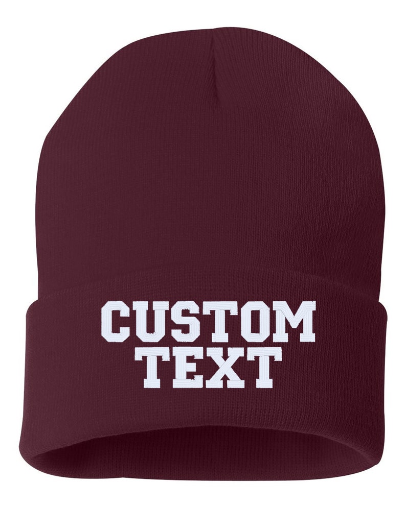 May include: A maroon beanie with the text "CUSTOM TEXT" in white.