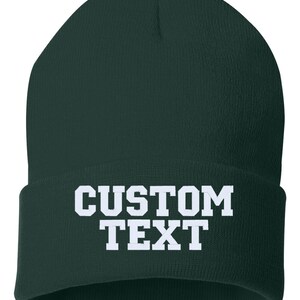 May include: A dark green beanie with white text that reads "CUSTOM TEXT".