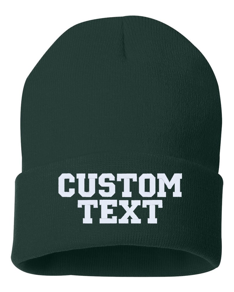 May include: A dark green beanie with white text that reads "CUSTOM TEXT".