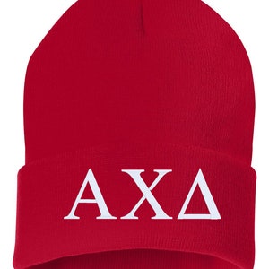Può includere: Berretto di lana rosso con lettere ricamate bianche "AXA" sul davanti.