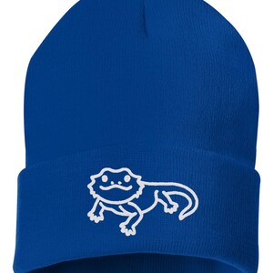 May include: A royal blue beanie with a white outline of a bearded dragon.