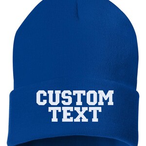 May include: A royal blue beanie with white text that reads "CUSTOM TEXT".