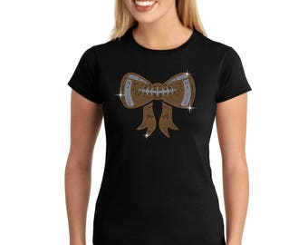 May include: A black t-shirt with a brown and silver rhinestone bow design. The bow is shaped like a football.