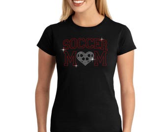 May include: Black t-shirt with red glitter lettering that says "Soccer Mom" with a silver glitter soccer ball in a heart shape.