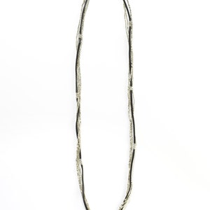 Puede incluir: Un collar de m&uacute;ltiples hilos con cuentas negras y plateadas. El collar est&aacute; hecho de m&uacute;ltiples hilos de cuentas que est&aacute;n entrelazados.