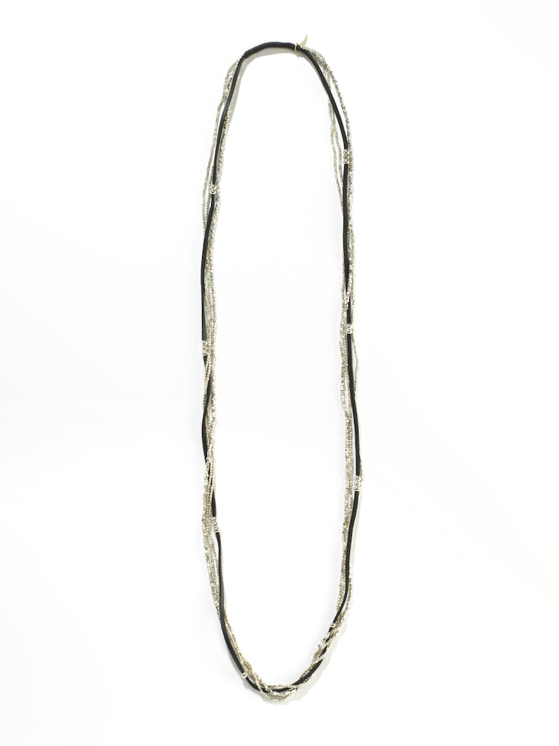 Puede incluir: Un collar de m&uacute;ltiples hilos con cuentas negras y plateadas. El collar est&aacute; hecho de m&uacute;ltiples hilos de cuentas que est&aacute;n entrelazados.