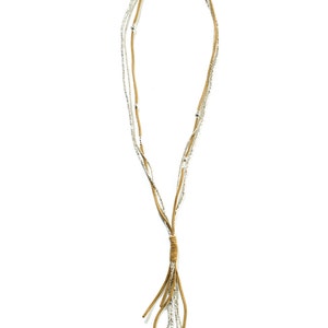May include: A multi-strand necklace with a brown suede tassel. The necklace is made of small silver beads and brown suede cord.
