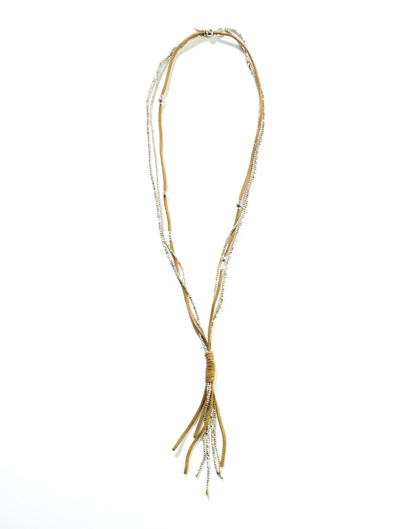 May include: A multi-strand necklace with a brown suede tassel. The necklace is made of small silver beads and brown suede cord.