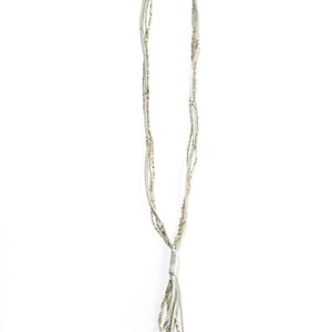 May include: A white leather necklace with a gold tassel. The necklace is made of multiple strands of leather with small gold beads.