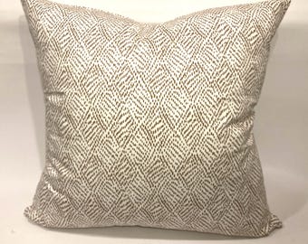 May include: A white throw pillow with a brown geometric pattern. The pattern is made up of small brown dots arranged in a chevron pattern.
