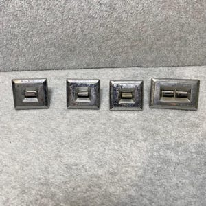 Puede incluir: Cuatro interruptores de bloqueo de ventanas y puertas cromados vintage. Tres son cuadrados y uno rectangular con dos interruptores. Los interruptores tienen un botón rectangular en el centro. La palabra "LOCK" es visible en un interruptor.