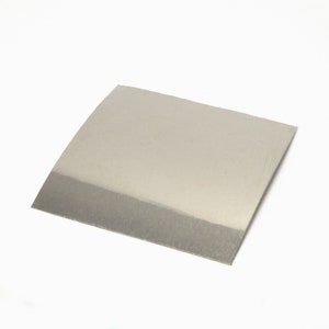 Op de afbeelding: Een vierkante, zilverkleurige metalen plaat met een licht gebogen rand. De plaat heeft een geborstelde textuur en een reflecterend oppervlak, wat suggereert dat deze is gemaakt van roestvrij staal of een vergelijkbaar materiaal. Het object is geïsoleerd op een witte achtergrond.