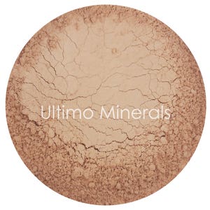 May include: A close-up of a light brown powder with a cracked surface. The text "Ultimo Minerals" is printed in white on the powder.