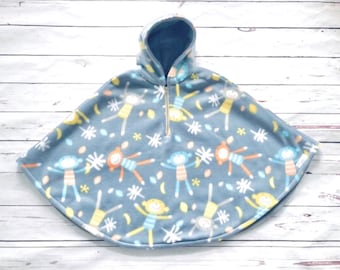 May include: A blue hooded fleece poncho with a colourful pattern of stick figures. The poncho has a zip closure and a hood.